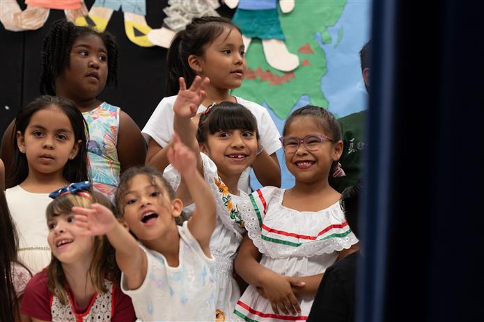 Students at Bologna Elementary School smile and wave to family in the crowd. 